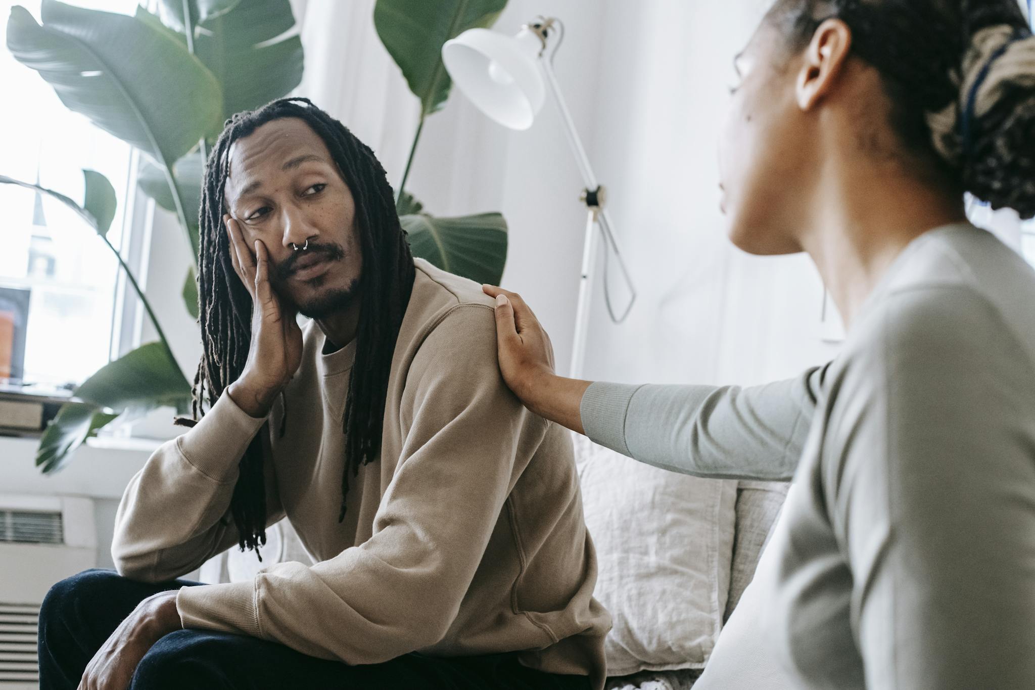 About 11 ethnic psychologist touching black depressed clients shoulder